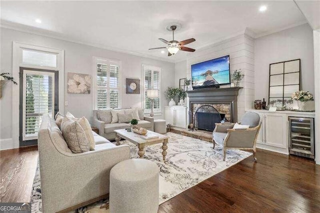 living room featuring dark hardwood / wood-style floors, ceiling fan, ornamental molding, a fireplace, and beverage cooler