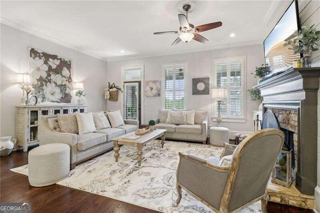 living room with crown molding, a fireplace, ceiling fan, and wood-type flooring