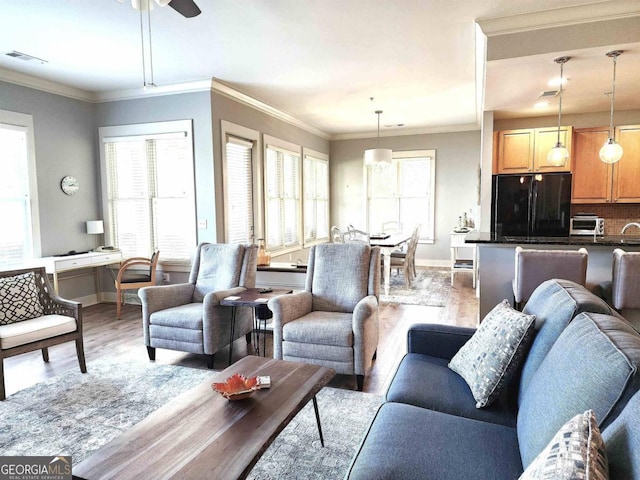 living room with crown molding, light hardwood / wood-style flooring, and ceiling fan