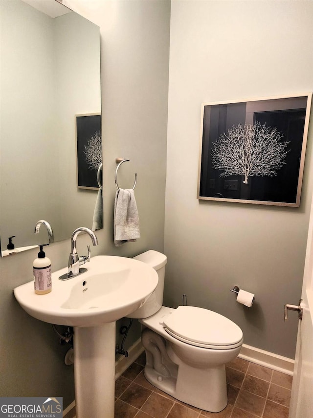 half bath featuring toilet and baseboards