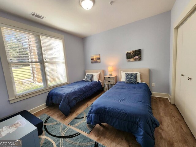 bedroom featuring baseboards, visible vents, and wood finished floors