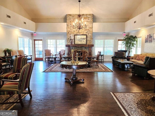 interior space with high vaulted ceiling, a healthy amount of sunlight, dark hardwood / wood-style floors, and a stone fireplace