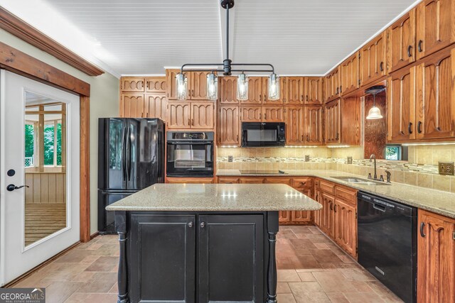 kitchen featuring a center island, sink, light stone counters, pendant lighting, and black appliances