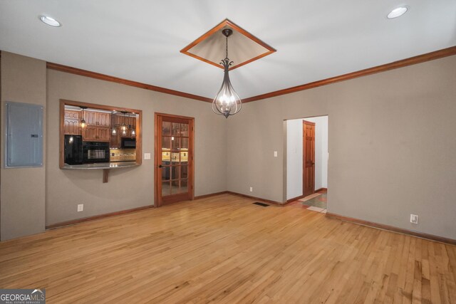 unfurnished living room featuring light hardwood / wood-style floors, crown molding, electric panel, and an inviting chandelier