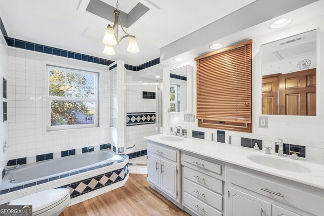 bathroom featuring decorative backsplash, vanity, hardwood / wood-style flooring, a relaxing tiled tub, and toilet