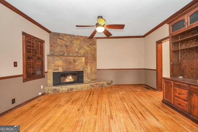 unfurnished living room with a fireplace, light hardwood / wood-style floors, ceiling fan, and crown molding