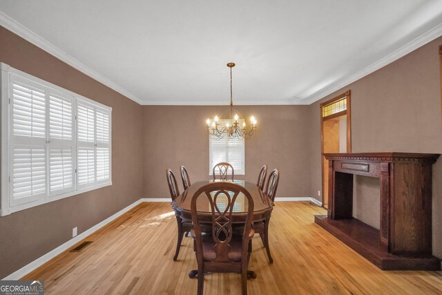 dining area featuring a notable chandelier, light wood-type flooring, and crown molding