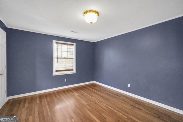 empty room with hardwood / wood-style flooring and crown molding