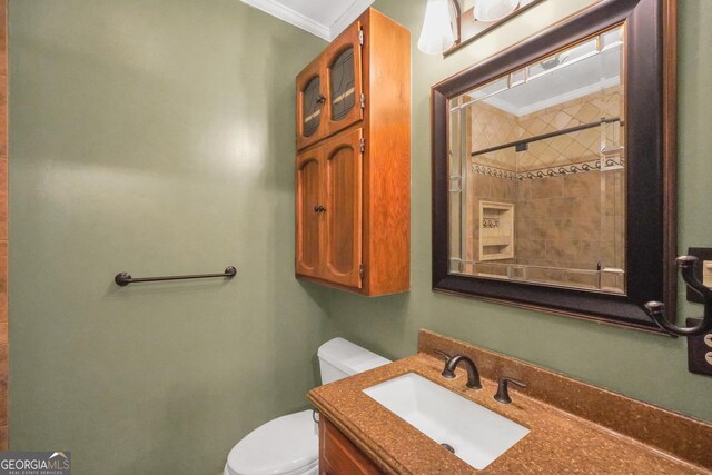 bathroom with tiled shower, vanity, toilet, and crown molding