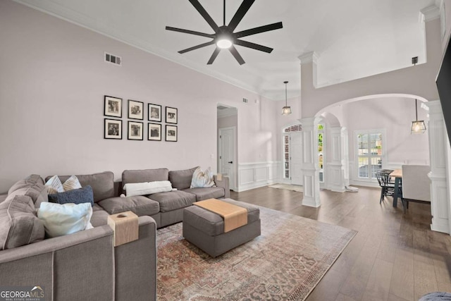 living room with dark hardwood / wood-style floors, ceiling fan, crown molding, and decorative columns