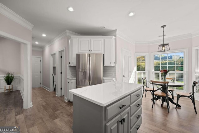 kitchen with stainless steel refrigerator with ice dispenser, dark wood-type flooring, pendant lighting, white cabinets, and a kitchen island