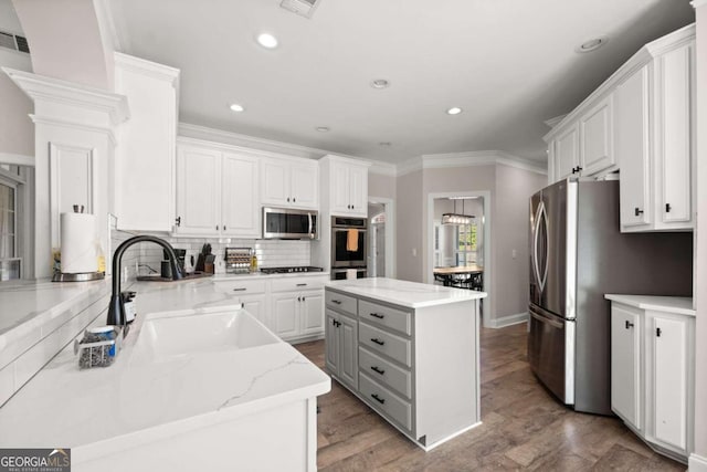 kitchen with a center island, white cabinets, decorative backsplash, appliances with stainless steel finishes, and light hardwood / wood-style floors