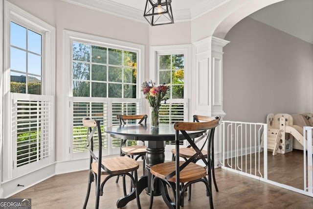 dining room with hardwood / wood-style flooring, ornate columns, crown molding, and a wealth of natural light