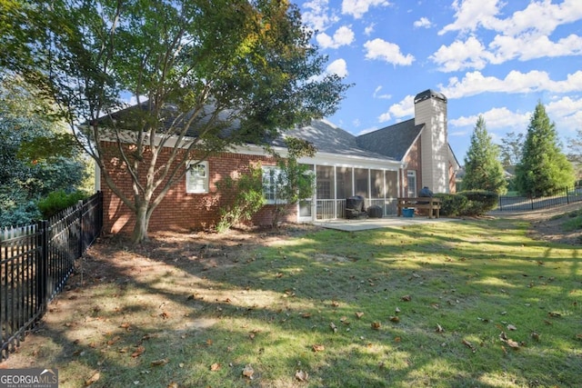 rear view of property with a sunroom, a patio area, and a lawn