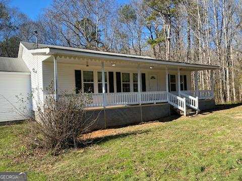 ranch-style house with covered porch, a front lawn, and a garage