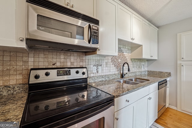 kitchen featuring stone counters, sink, a textured ceiling, white cabinetry, and stainless steel appliances