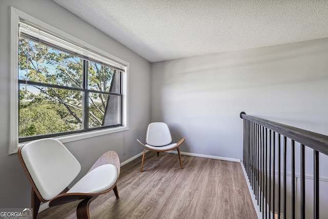 living area with a textured ceiling and hardwood / wood-style floors