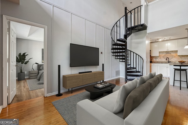 living room with sink, light hardwood / wood-style floors, and a high ceiling