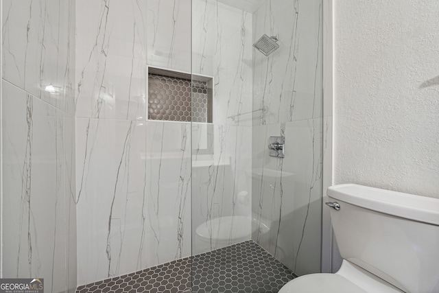 bathroom featuring a tile shower and toilet