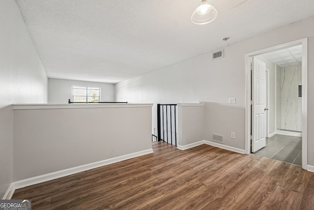 empty room featuring a textured ceiling and wood-type flooring