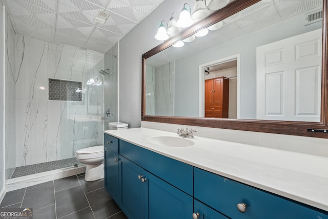 bathroom with vanity, toilet, tiled shower, and tile patterned flooring