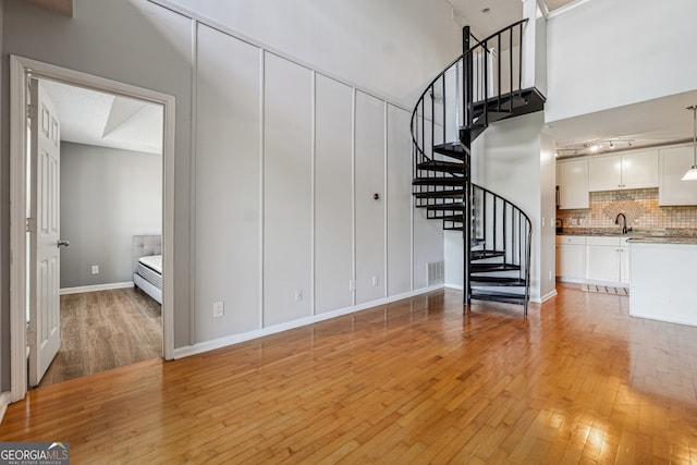 staircase featuring sink, a high ceiling, and hardwood / wood-style floors