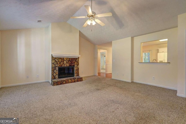 unfurnished living room featuring ceiling fan, a stone fireplace, a textured ceiling, and vaulted ceiling