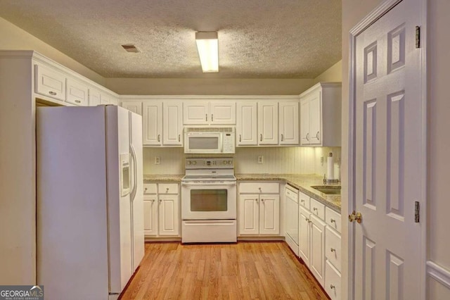 kitchen featuring light hardwood / wood-style flooring, sink, white cabinets, a textured ceiling, and white appliances