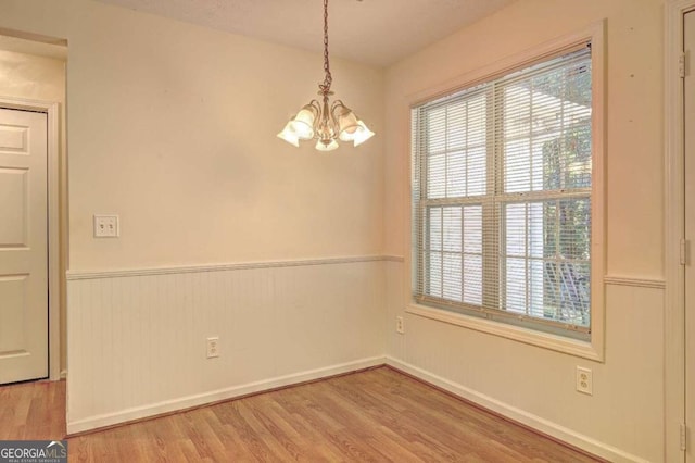 unfurnished room featuring a notable chandelier and light wood-type flooring