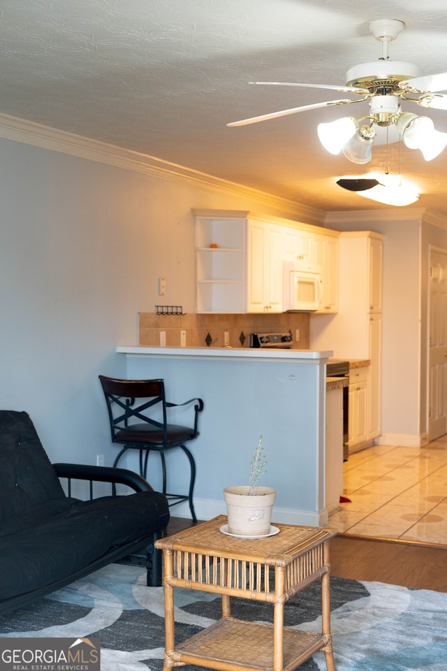 kitchen with crown molding, white cabinetry, light wood-type flooring, and ceiling fan