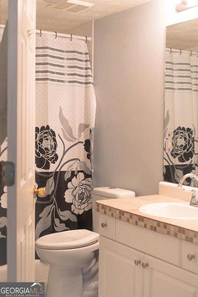 bathroom with toilet, a textured ceiling, and vanity