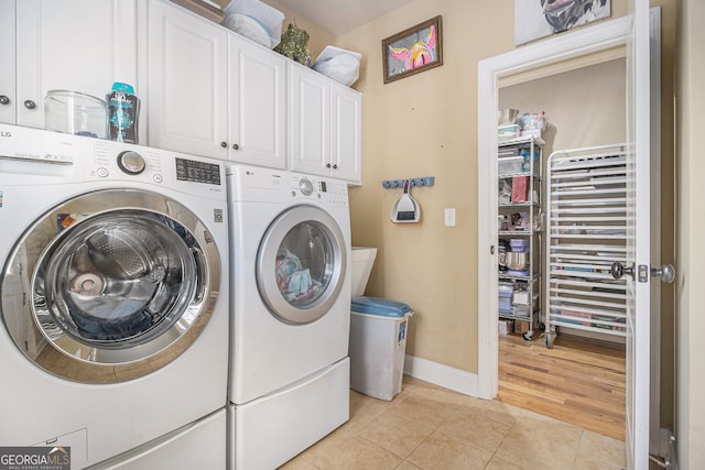 laundry area with light tile patterned floors, cabinets, and washing machine and clothes dryer