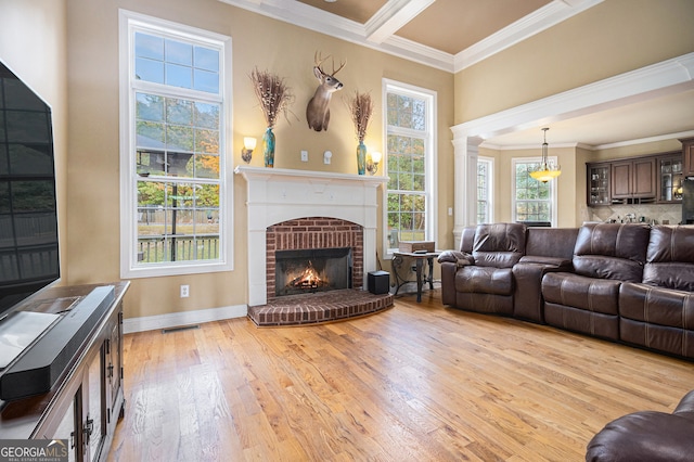 living room featuring ornamental molding, decorative columns, a fireplace, and light wood-type flooring