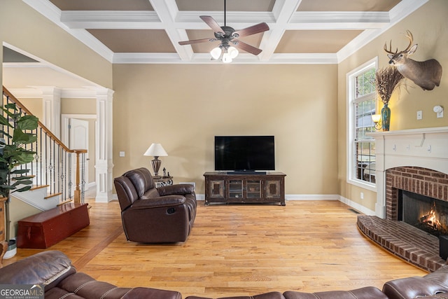 living room featuring light hardwood / wood-style flooring, ceiling fan, a brick fireplace, and crown molding