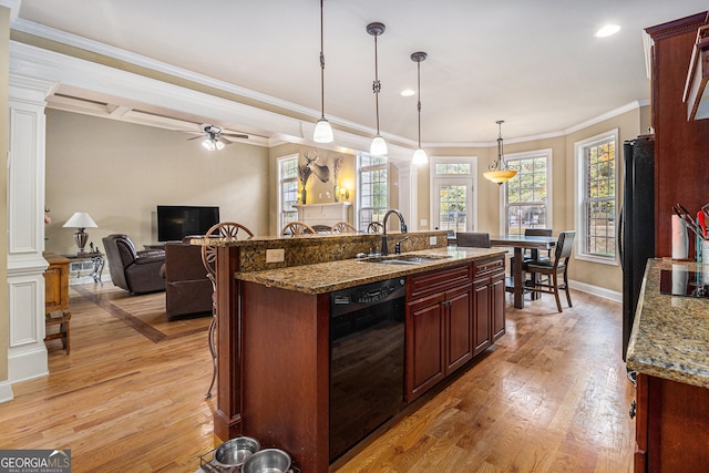 kitchen featuring hanging light fixtures, sink, black appliances, decorative columns, and light hardwood / wood-style floors