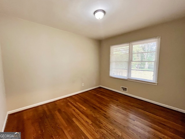 unfurnished room with dark wood-type flooring