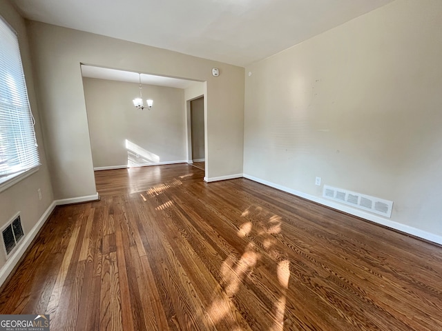 unfurnished room with hardwood / wood-style flooring and an inviting chandelier