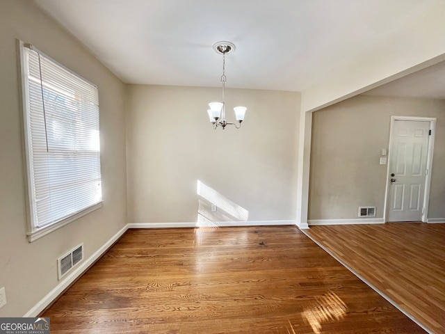 unfurnished dining area featuring hardwood / wood-style floors and a chandelier