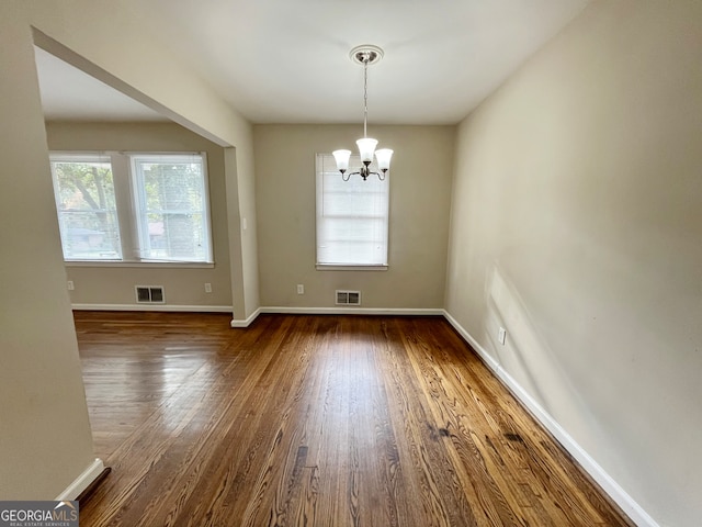 unfurnished dining area with dark hardwood / wood-style flooring and a notable chandelier