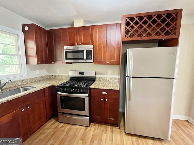 kitchen with light hardwood / wood-style floors, stainless steel appliances, sink, and light stone counters