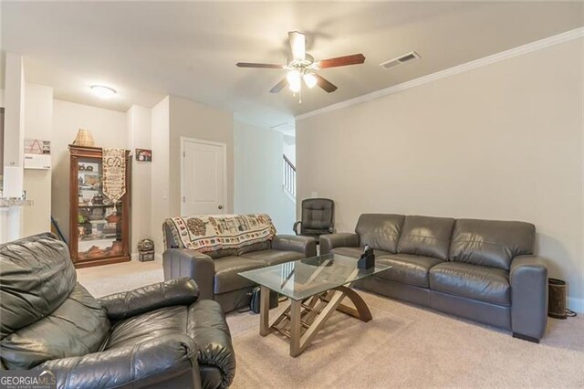 living room with ornamental molding, light carpet, and ceiling fan