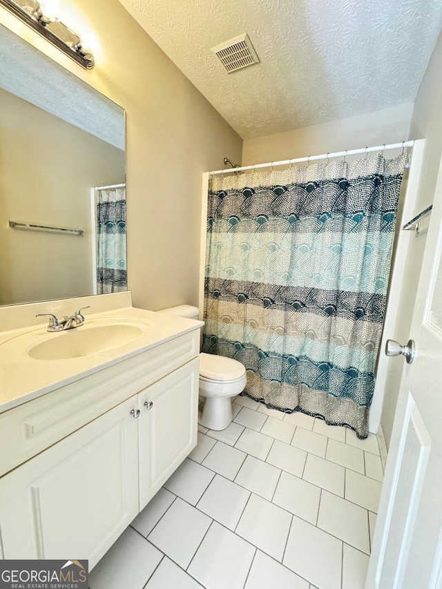 bathroom with a textured ceiling, walk in shower, toilet, vanity, and tile patterned flooring