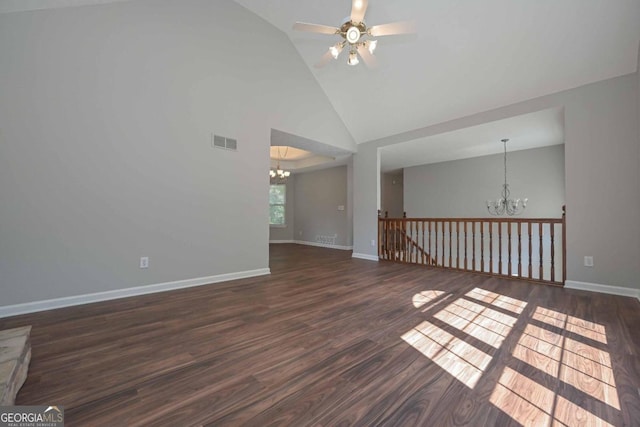 empty room with high vaulted ceiling, dark wood-type flooring, and ceiling fan with notable chandelier