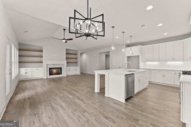 kitchen with a fireplace, vaulted ceiling, dishwasher, white cabinetry, and an island with sink