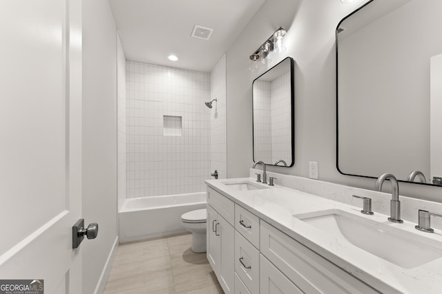 full bathroom with tile patterned floors, vanity, tiled shower / bath, and toilet