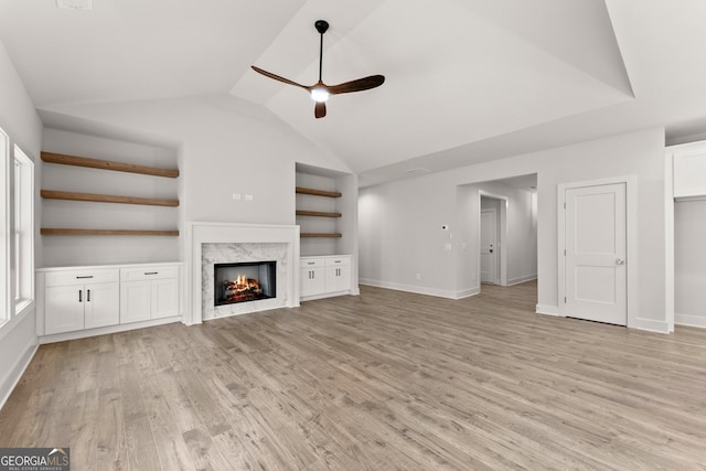 unfurnished living room featuring light wood-type flooring, ceiling fan, lofted ceiling, and a premium fireplace