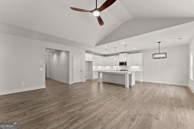 unfurnished living room featuring hardwood / wood-style flooring, ceiling fan, and high vaulted ceiling