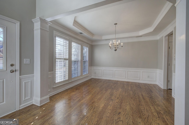 unfurnished dining area with dark hardwood / wood-style floors, a raised ceiling, crown molding, and a chandelier