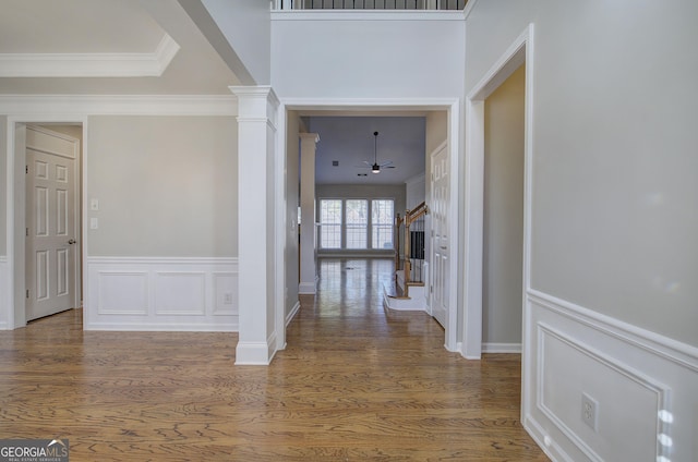 hall featuring dark wood-type flooring, decorative columns, and ornamental molding