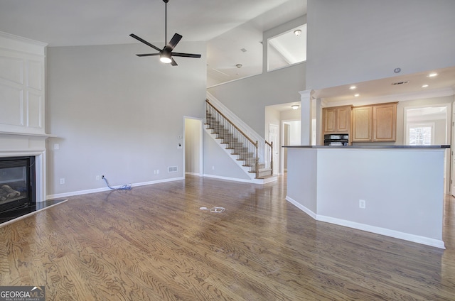 unfurnished living room with hardwood / wood-style flooring, high vaulted ceiling, and ceiling fan